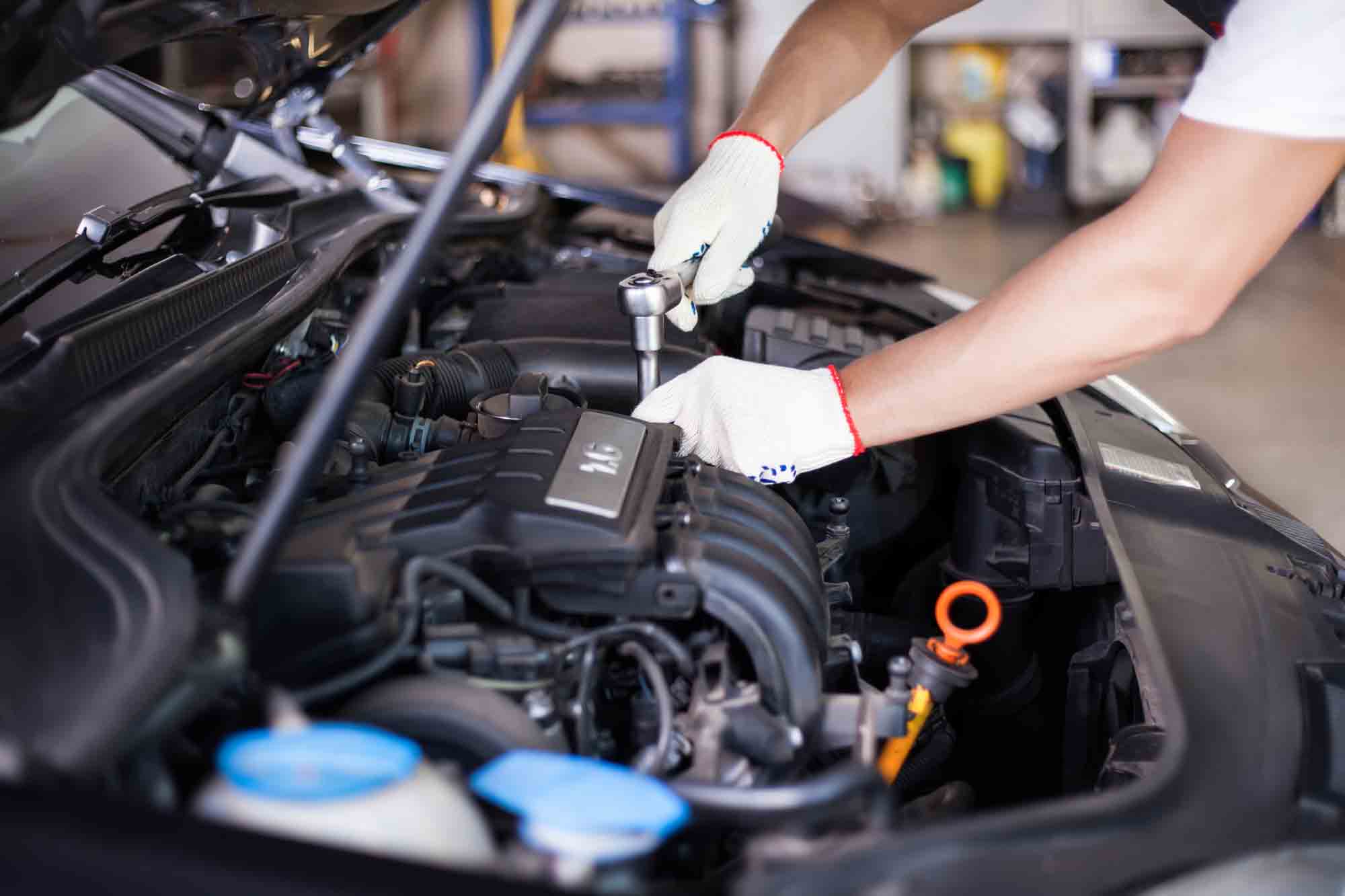 A mechanic performing maintenance on a car engine using a ratchet tool